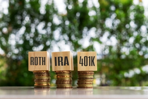 An image depicts three stacks of coins, each topped with a small wooden block. One reads Roth, another reads IRA and another reads 401(k). This helps explain 401(k) limits. 