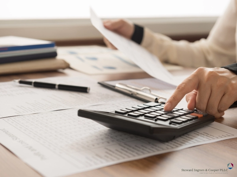Woman using a calculator in an office. bookkeeping vs accounting concept.