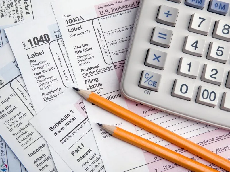 1040 tax form, pencils, and calculator. Image accompanies the blog "North Carolina Income Tax Guide."