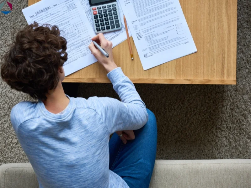 A business owner familiarizes himself with non taxable income examples for tax purposes but using a calculator and filling out a tax form. 