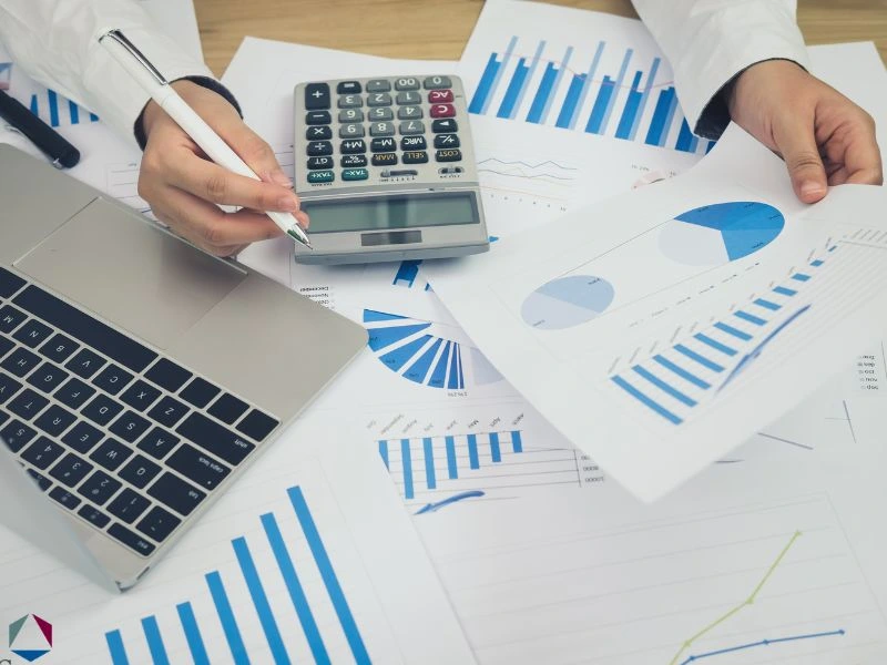 A man is calculating finances using a calculator and a budget spreadsheet. This featured image is for the article about business debt consolidation.
