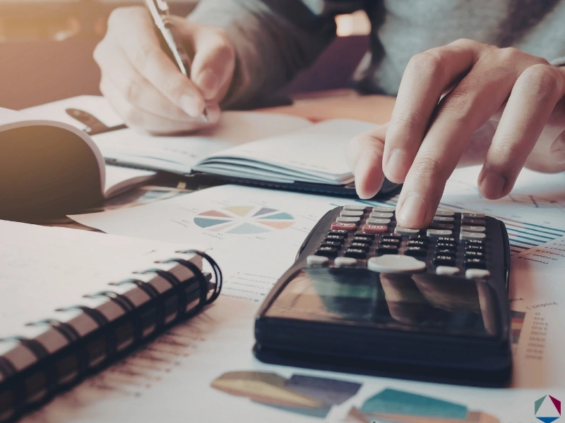 Woman using a calculator, highlighting the blog regarding the NC Standard Deduction, should i claim the n.c. standard deduction, standard vs itemized deduction, and NC itemized deductions.