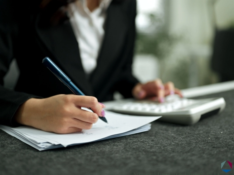 Woman writing with a pen, highlighting the blog regarding the NC Standard Deduction, should i claim the n.c. standard deduction, and standard vs itemized deduction.