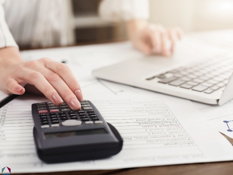 A woman's hands using a calculator, highlighting the blog regarding the NC Standard Deduction, should i claim the n.c. standard deduction, standard vs itemized deduction, and NC itemized deductions.