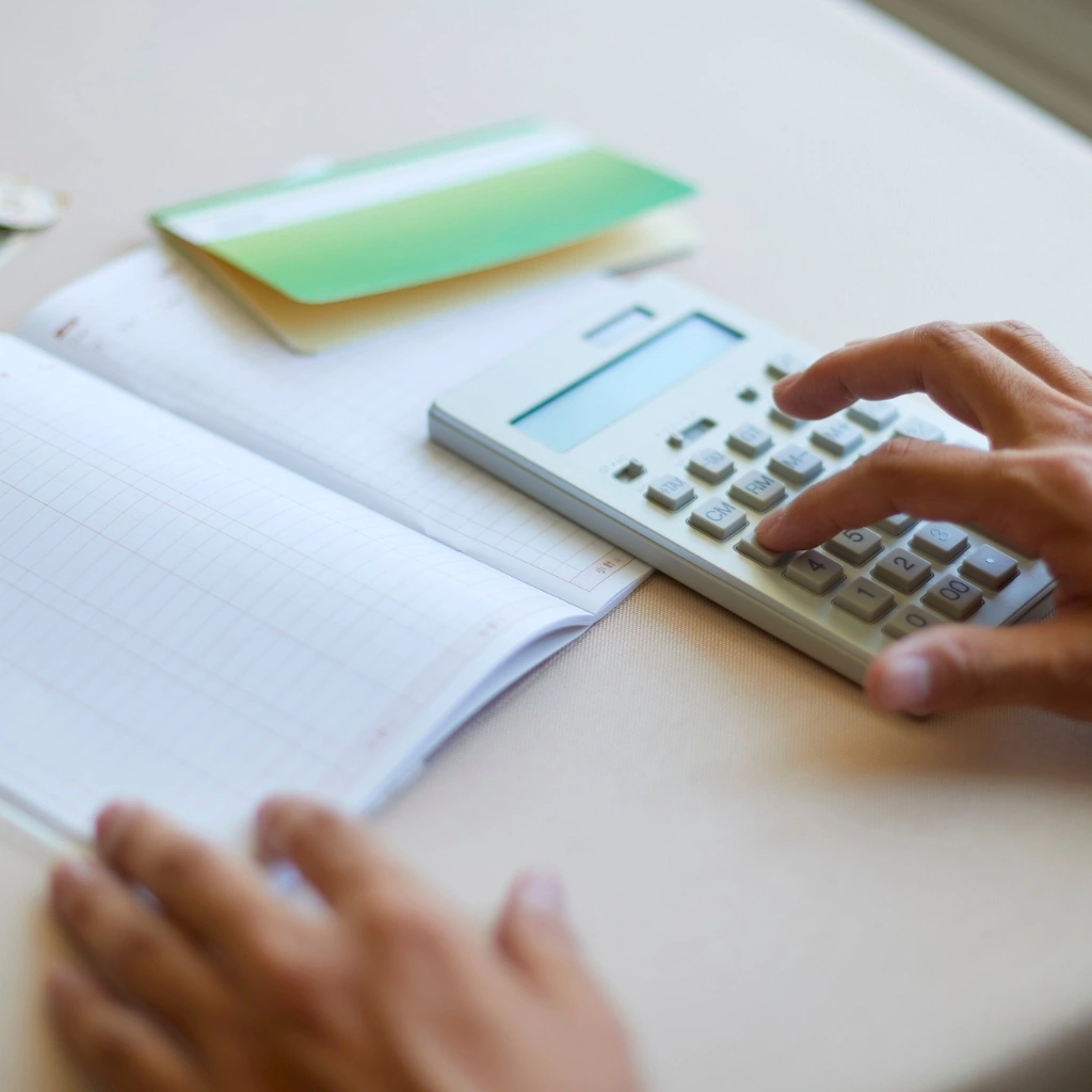 a business tax accountant in Raleigh-Durham, NC prepares a general ledger using paper and a calculator.