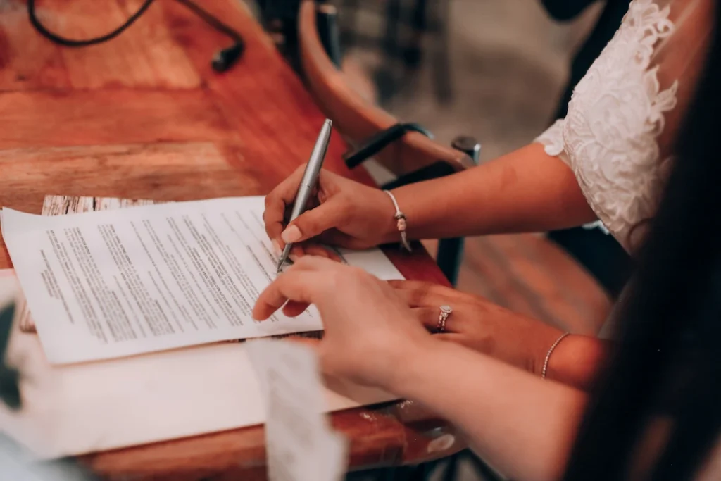 Hands signing an important document at a wooden table. Image complements the blog titled Multi State Tax Filing.