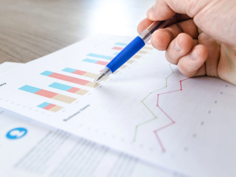 A close-up of a hand with a pen analyzing tax planning on investment gains.