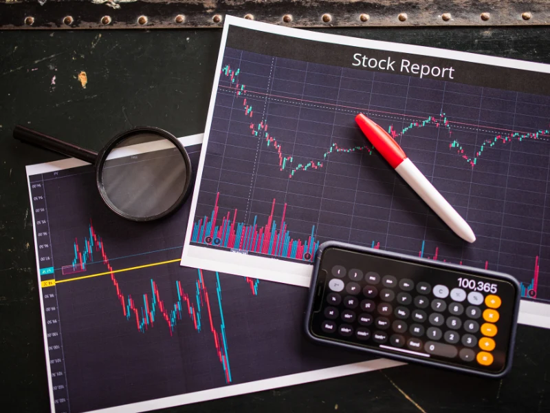 Stock report with charts, calculator, and magnifying glass, showing tax planning on investment gains.